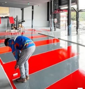 Instalación técnica de piso epóxico industrial de alto tráfico con líneas de señalización rojas y grises en Tláhuac